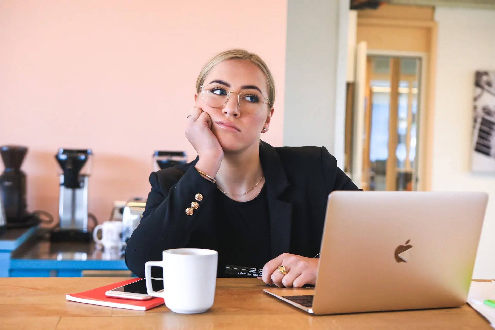 Student at a laptop with her phone, reviewing social media accounts before a US visa interview